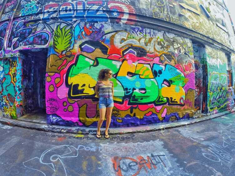 Nina in Melbourne, Australia standing in front of a graffitied wall.