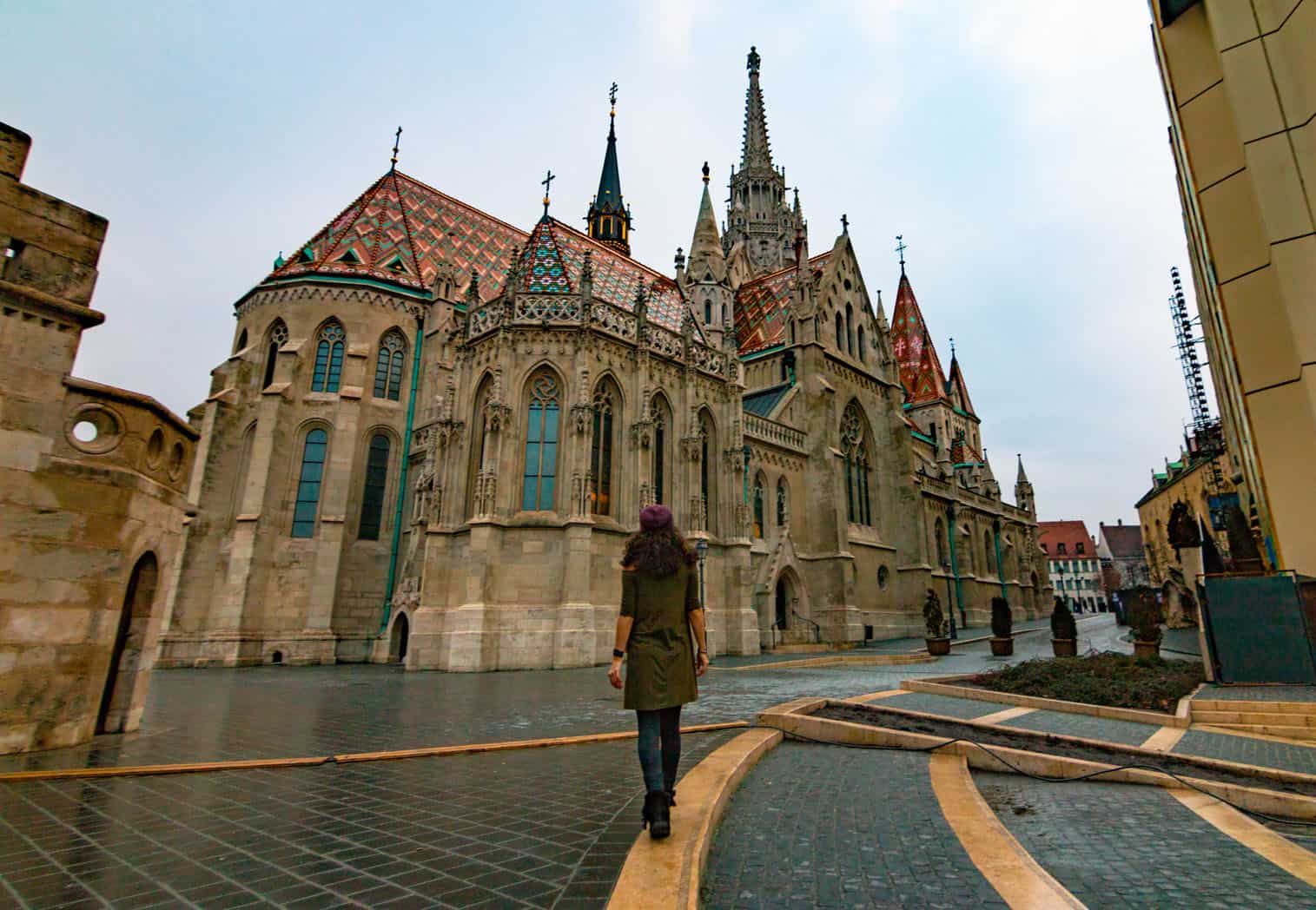 Nina walking through a historic section of Budapest with a huge gothic building in front of her.