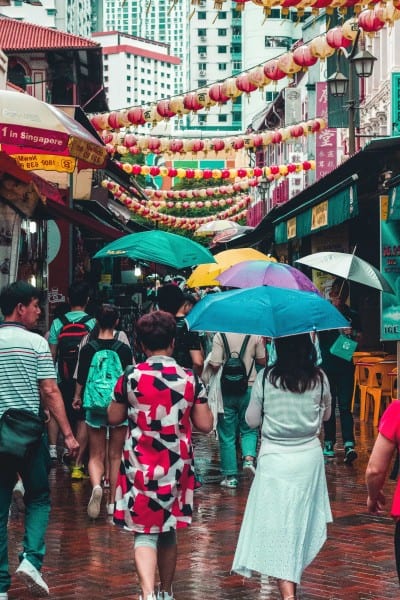 Singapore street with people using umbrellas on a rainy day.