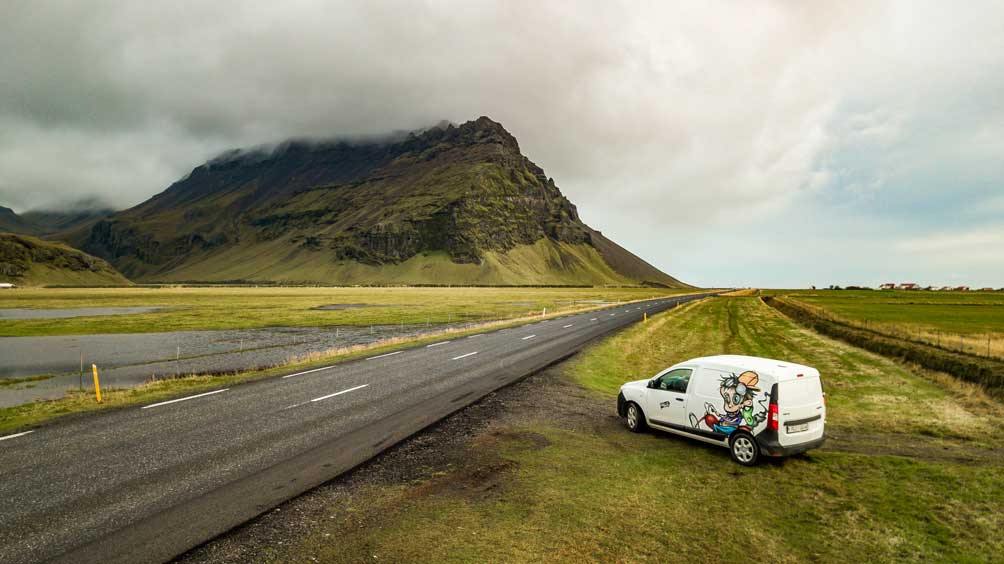 A Kuku campervan parked off the side of the famous Icelandic ring road with a huge mountain backdrop.