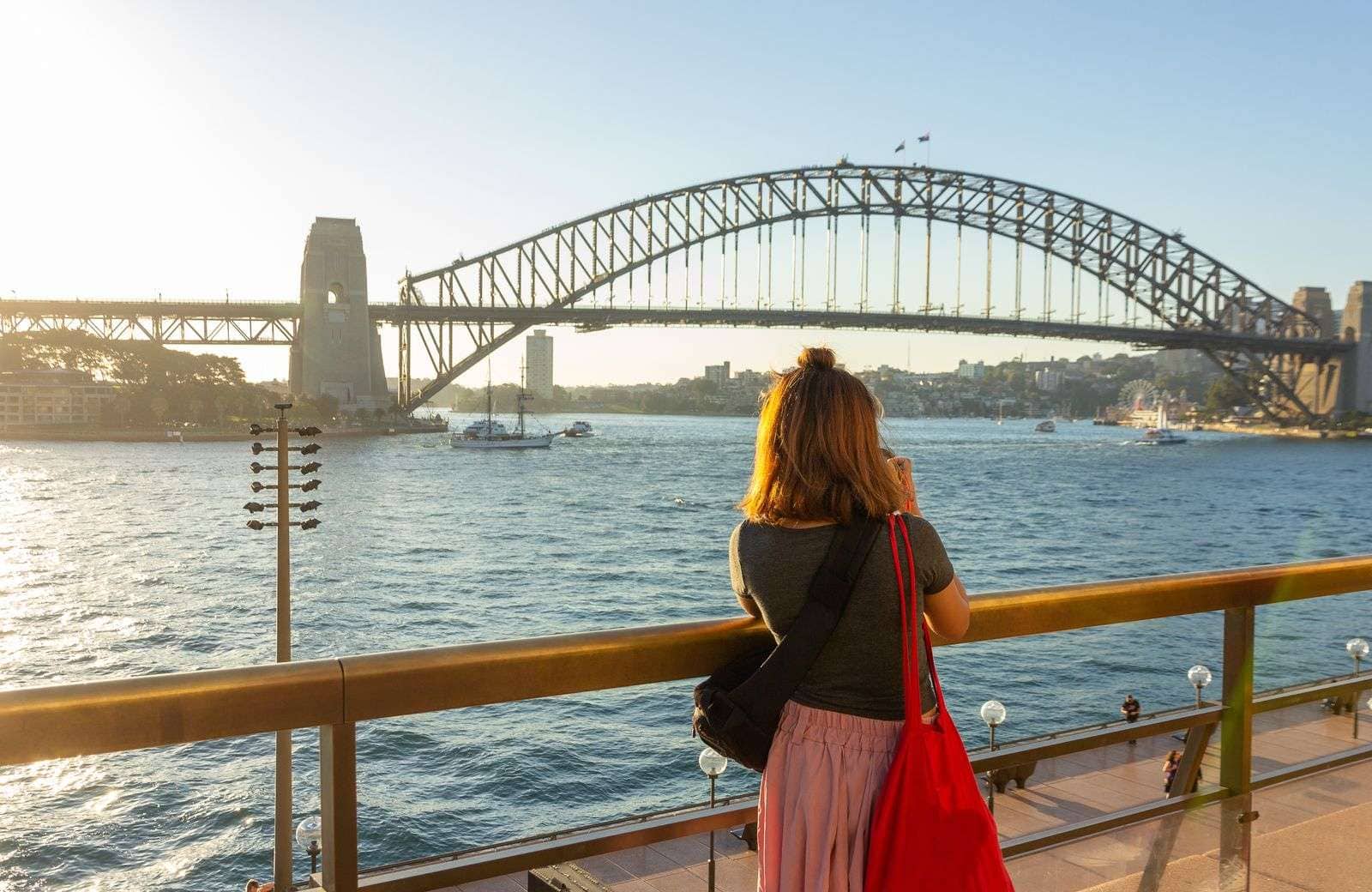A woman taking a picture of the Sydney bridge.