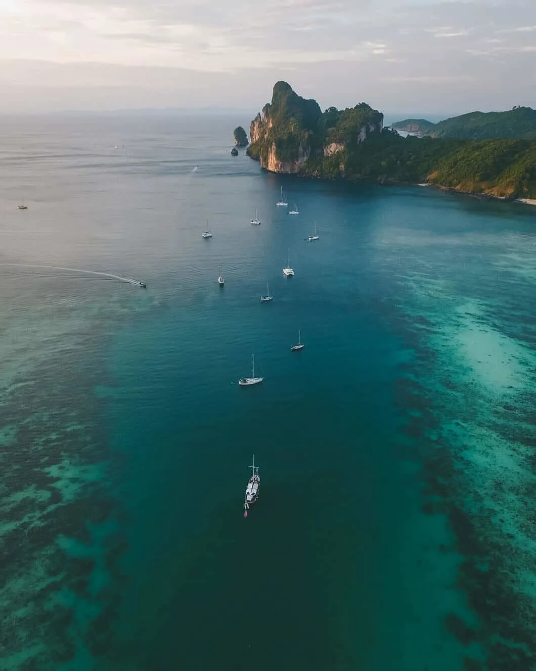 Many boats anchored out in the amazing ocean waters of Krabi, surrounded by coral reefs.