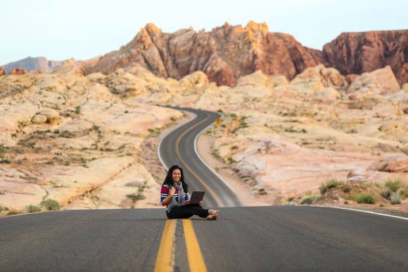 girl sitting in the middle of the road with a laptop