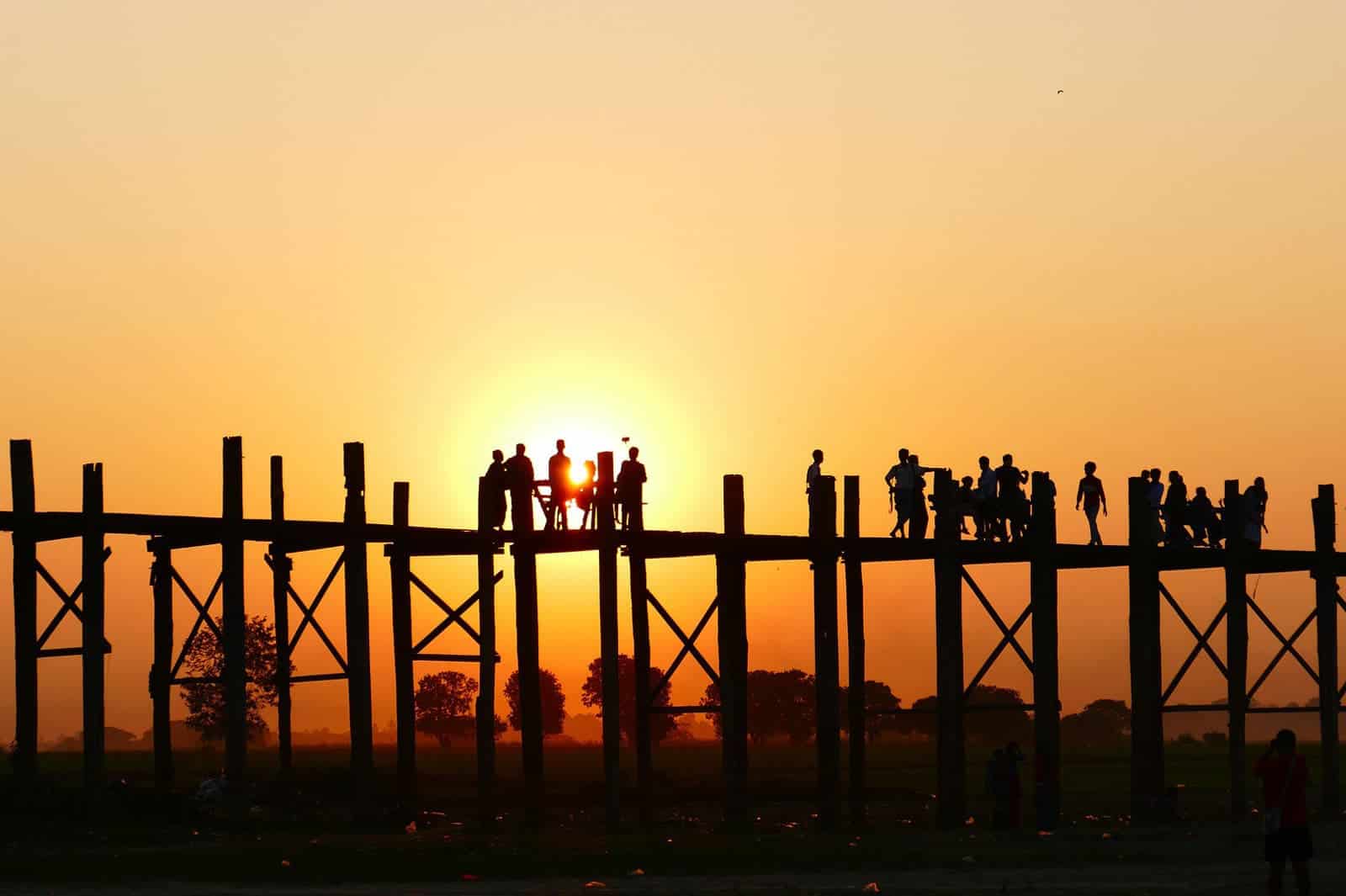 people on bridge during sunset