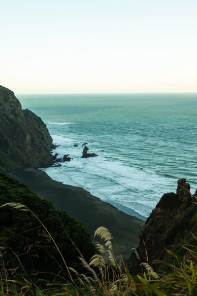 Mercer bay track walk in Piha with rocky mountain and ocean view