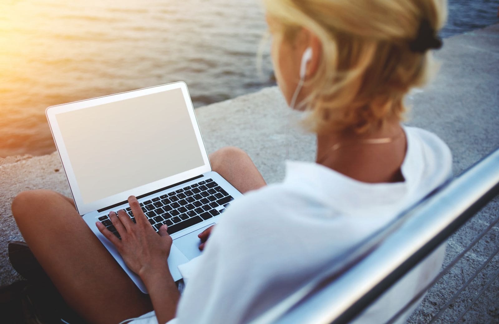 Digital nomad woman on laptop with sun burst in the left corner