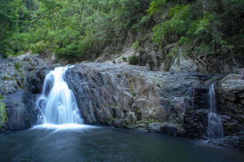 Waterfall falling over rock wall into pool at Crystal Cascades - one of the top things to do in Cairns