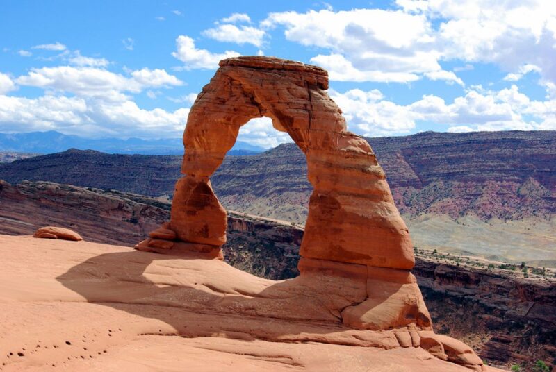 Rock arch with mesas and blue sky in background in Arches National Park