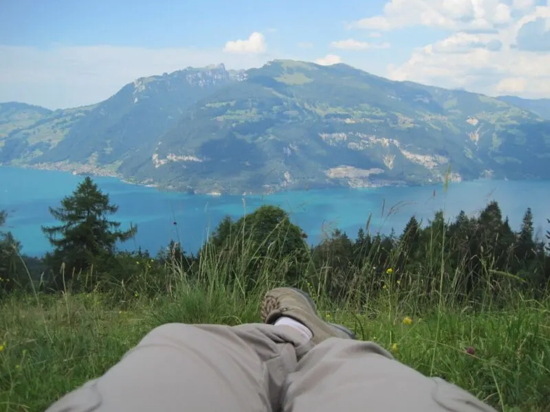 Person's legs lying on grass with view over lake and mountain in distance