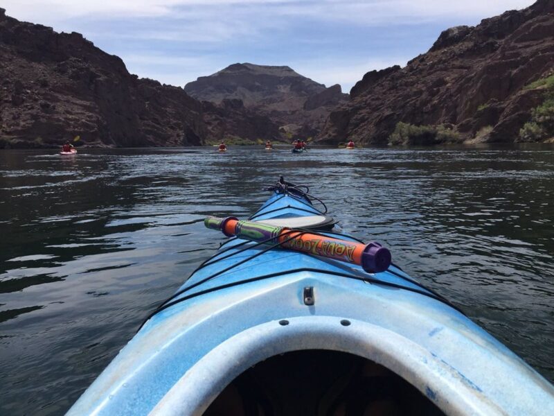 Front of kayak with on the river surrounded by canyons - one of the top things to do in Moab