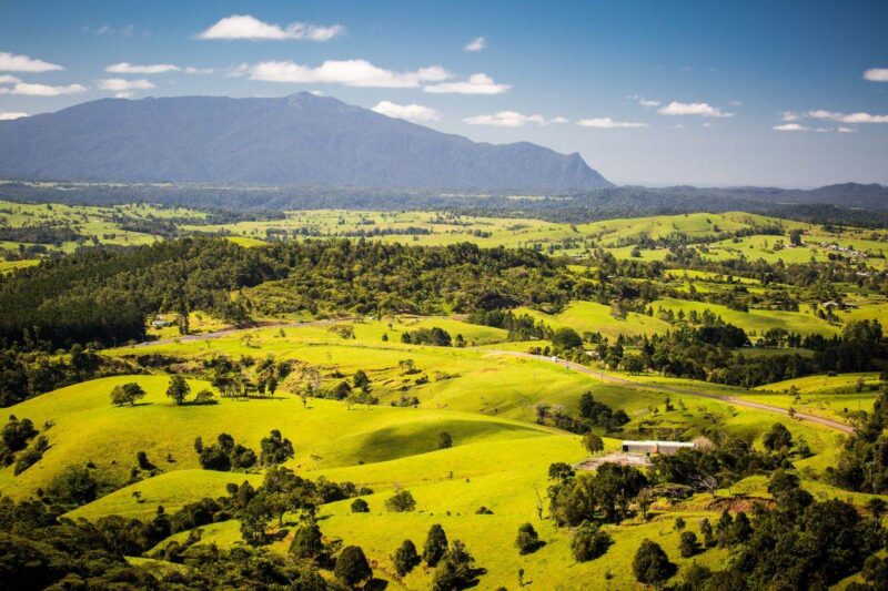 Aerial view over green fields with mountains in background at Millaa Millaa - one of the best places to visit near Cairns