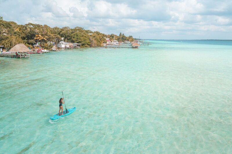 Paddleboarder in turquoise ocean with spit of land in background in Mexico