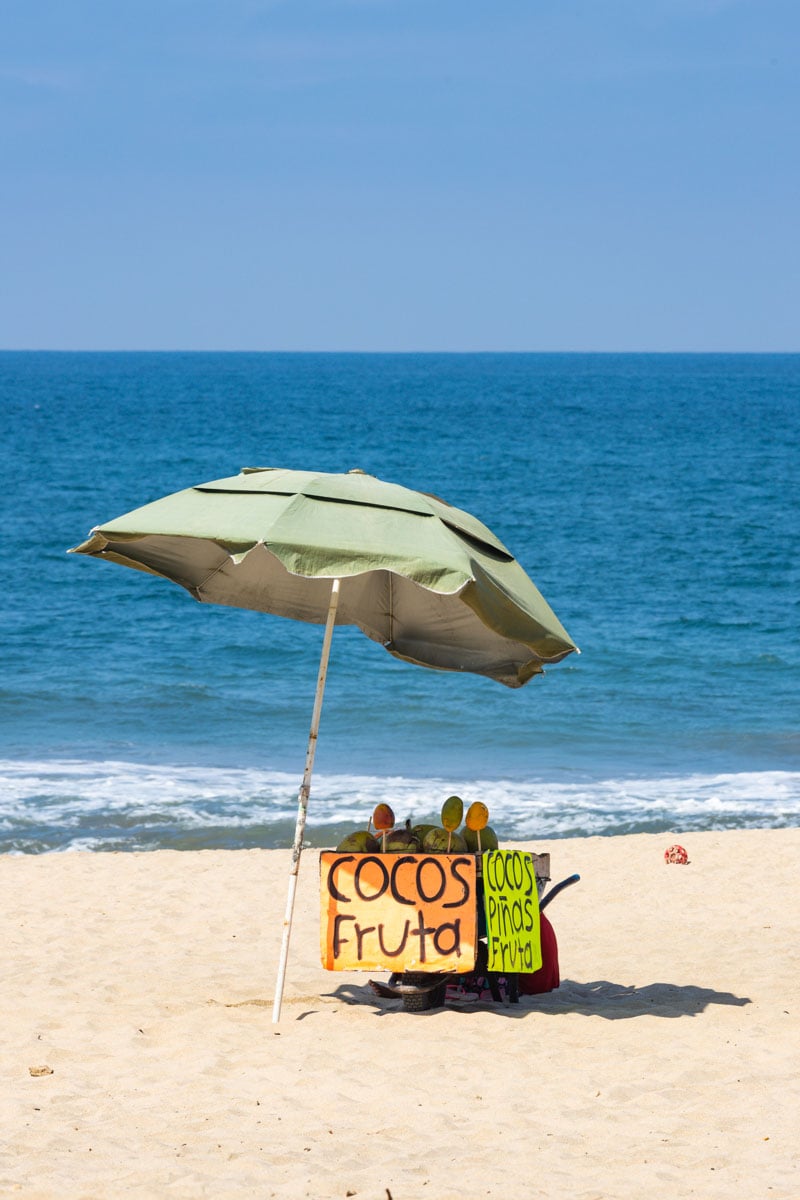 Beach umbrella and fruit stand on San Pancho beach with ocean in the background