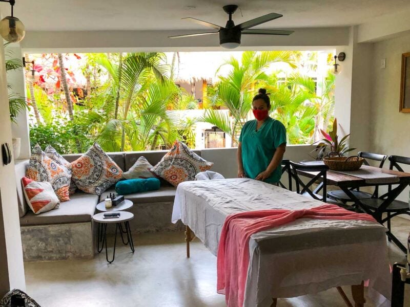 Masseuse standing by massage table in room with palms seen through window - getting a massage in your room is one of the top things to do in Sayulita