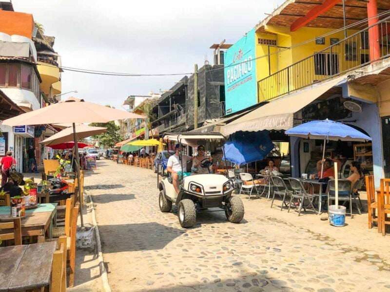 Golf cart on the street with buildings on either side in Sayulita