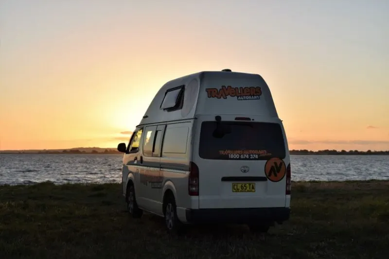 Campervan parked in front of the ocean as sunset - campervanning is one of the best things to do in Queensland