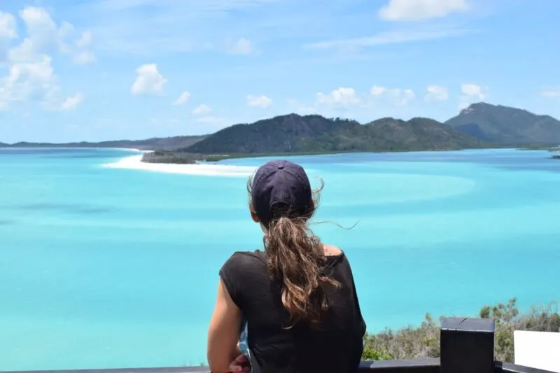 Sitting woman from the back looking out at view over Whitsunday Islands and ocean - doing a Whitsundays cruise is one of the best things to do in Queensland