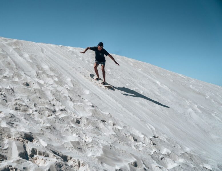 Man sandboarding down white sand dune in Lancelin - one of the best things to do on the West Coast of Australia