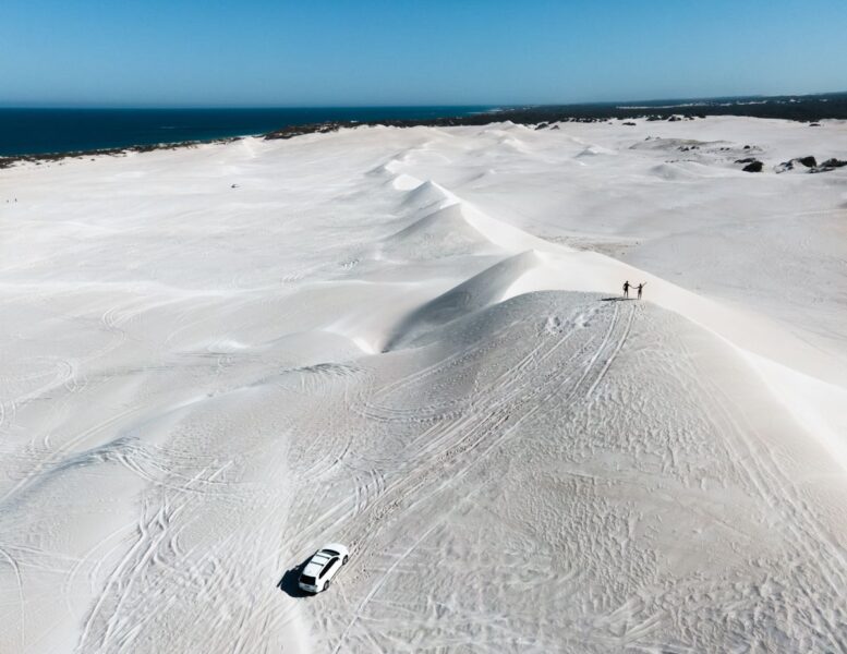 View over undulating white sand dunes with people in the distance walking on them at Lancelin