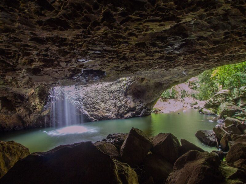 View of waterfall falling into a pool inside a cave at Natural Bridge - one of the best things to do on the Gold Coast