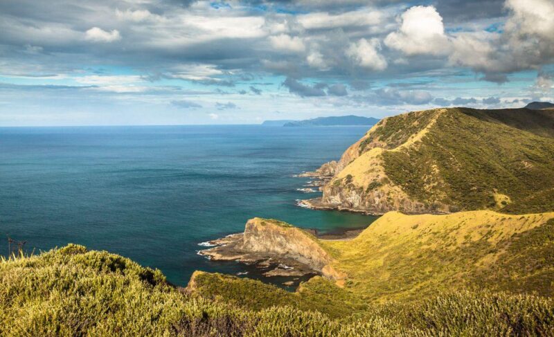 Aerial view over coastline and ocean with clouds above at Spirits Bay in Northland