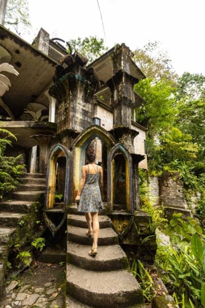 Nina walking up path leading up to unusual sculpture surrounded by foliage in Las Pozas Xilitla Jardin, Huasteca Potosina