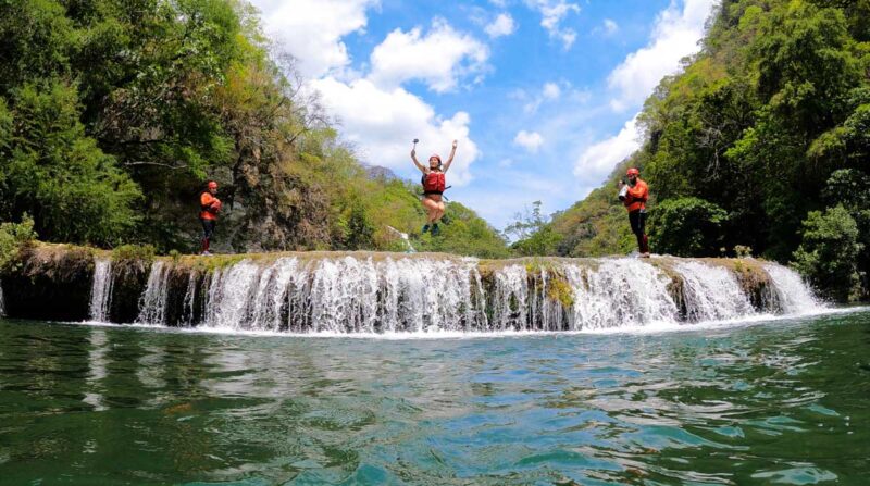 Three people in the air after jumping from Micos waterfall with pool below them on a Huasteca Potosina tour