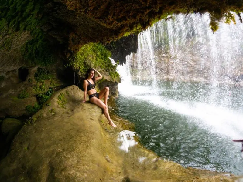 Nina posing on rock in cave behind Micos Waterfall on one of the Huasteca Potosina tours in Mexico