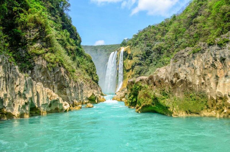 Tamul Waterfall with pool of turquoise water in front and forested rocky cliffs on each side in Huasteca Potosina