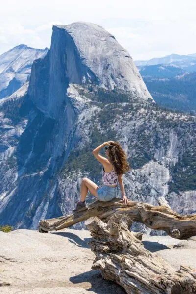 Woman sitting on log at Glacier Point with view of the mountain in Yosemite