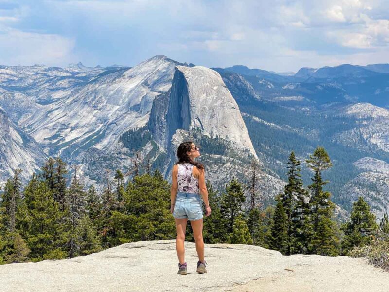 Woman on cliff overlooking Sentinel Dome on Yosemite road trip