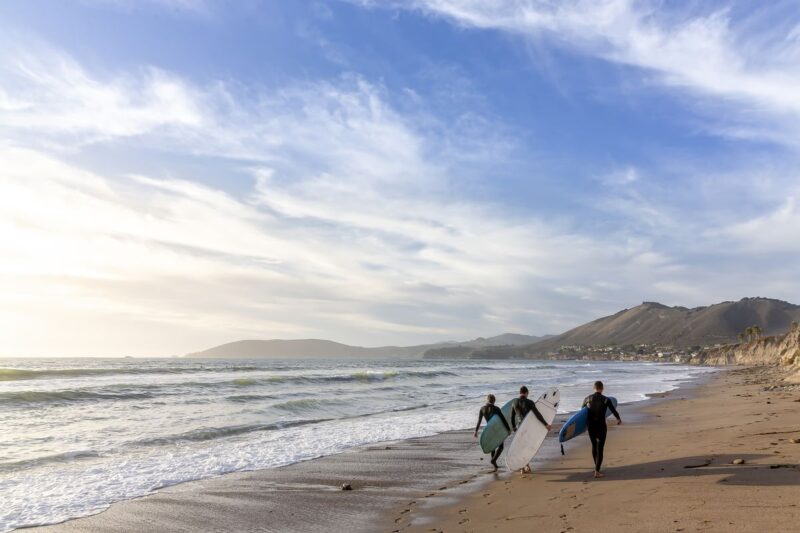 Surfers walking along Pismo Beach