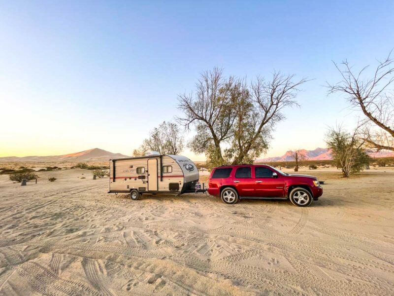 Car pulling camper van in the Mojave Desert, California
