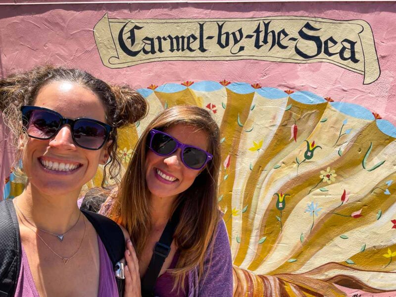 Women in front of sign for Carmel-by-the-Sea in Monterey