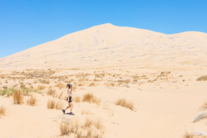Woman on sand dunes on the Kelso Dunes Hike in the Mojave Desert on a California road trip