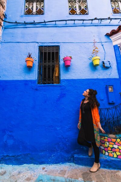 Me in Chefchaouen in Morocco next to a blue wall.