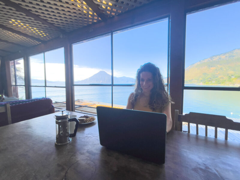 Woman working on laptop with view of Lake Atitlan, Guatemala 