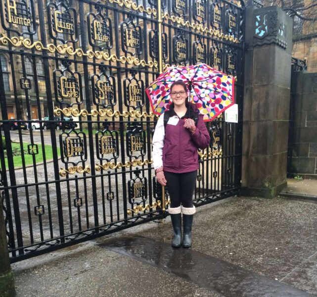 Woman under umbrella in Glasgow working in the UK as a foreigner