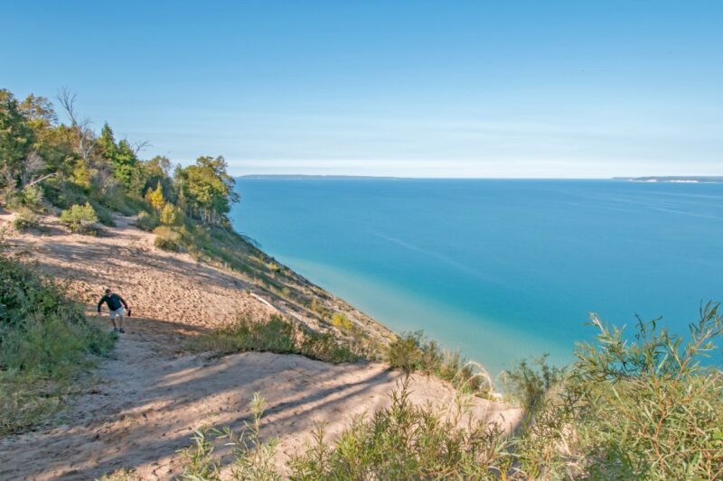 Man climbing dunes at Pyramid Point on hikes in Northern Michigan