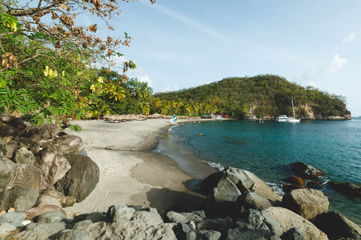 Anse Chastanet Beach with boats and a hill in the distance and rocks at the bottom.