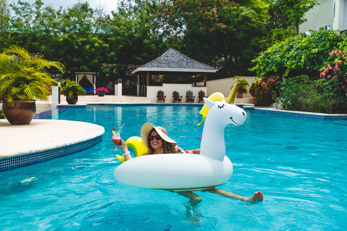 Woman in pool using a unicorn floaty and holding a drink at Calabash Cove in St Lucia.