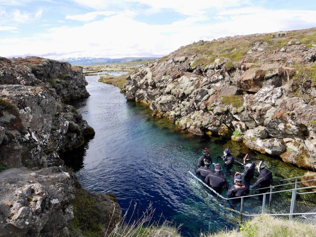 Snorkelers entering water at Silfra Rift day tours from Reykjavik