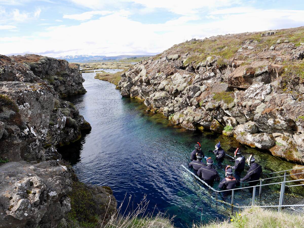 Snorkelers entering water at Silfra Rift day tours from Reykjavik
