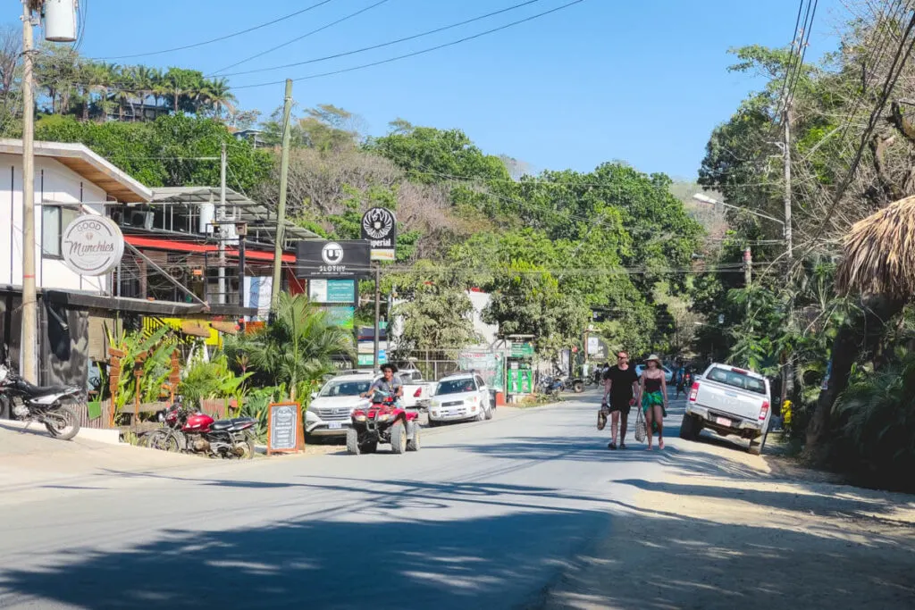 A man riding and ATV and a couple of tourists walking along the main street in Santa Teresa. A man riding and ATV and a couple of tourists walking along the main street in Santa Teresa.