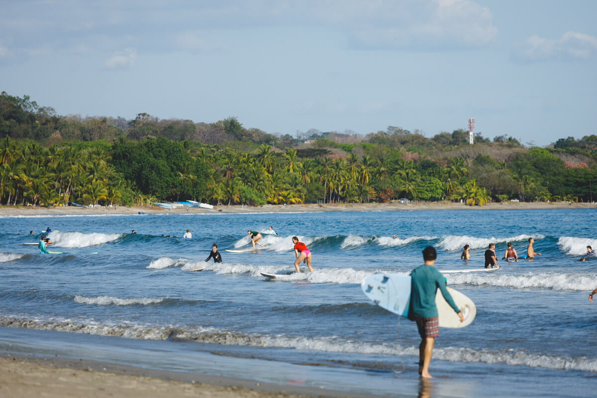 Lots of tourists at Samara Beach hitting the waves on surfboards.