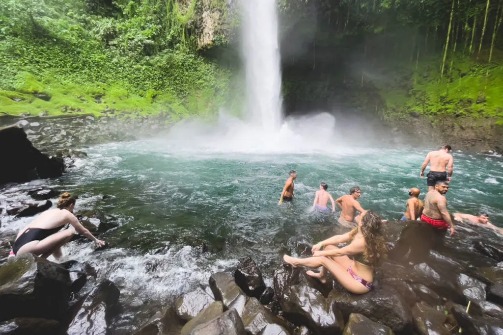 People swimming in the plunge pool of the waterfall.