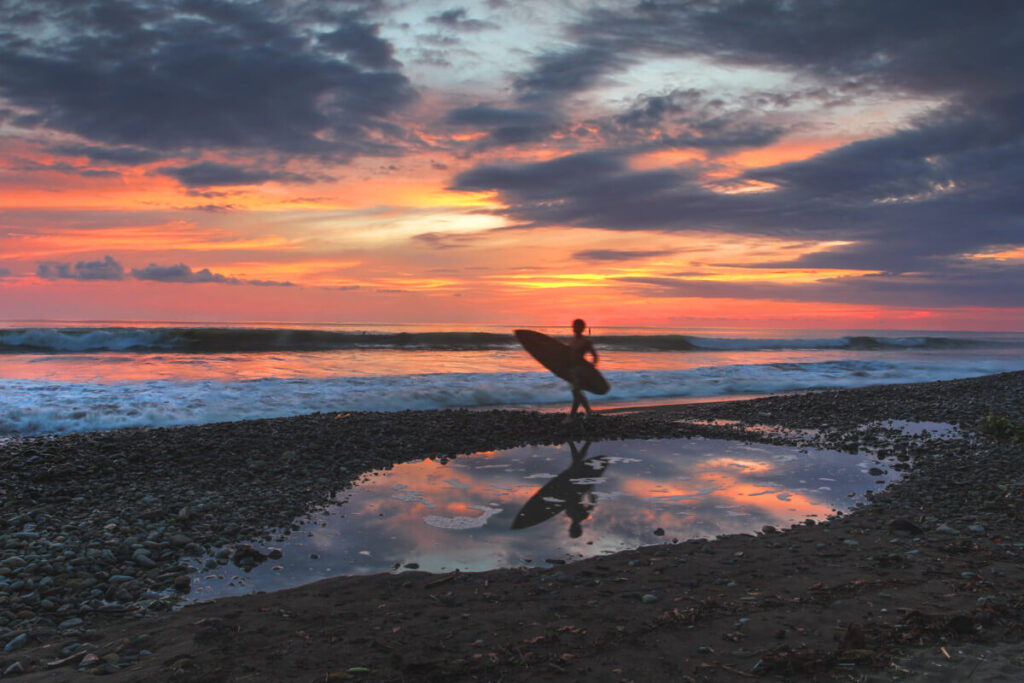 A surfer walking along Dominical Beach in Costa Rica.