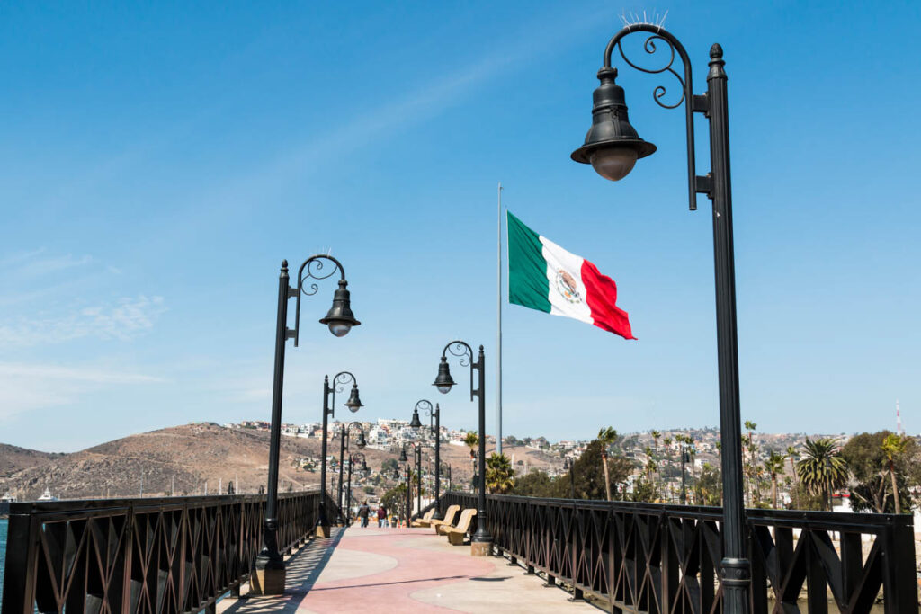 A pedestrian bridge and Mexican flag across the waterfront.