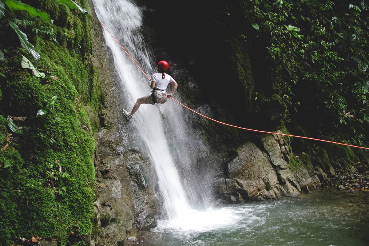 A tourist rappelling down the side of a waterfall.