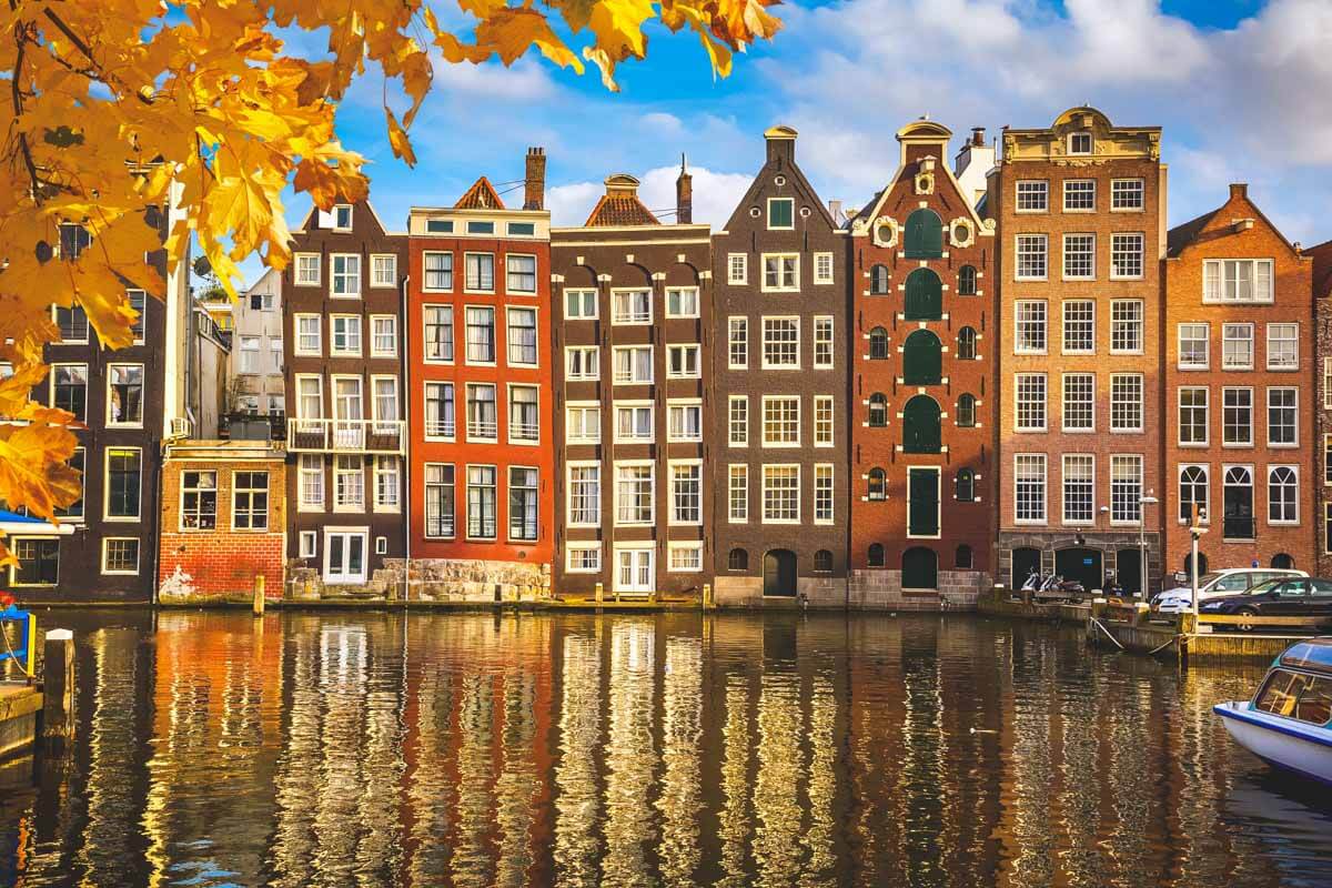 Classic Dutch town houses line up along the river in Amsterdam at golden hour during the fall.
